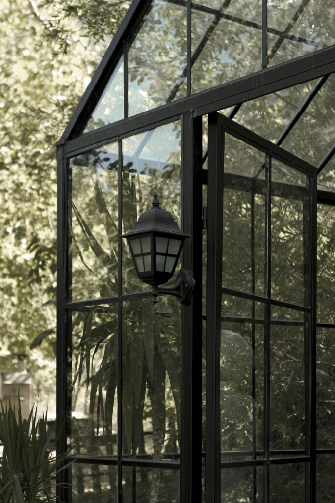 A stylish greenhouse in Manisa, Türkiye featuring glass panels and a vintage lamp.